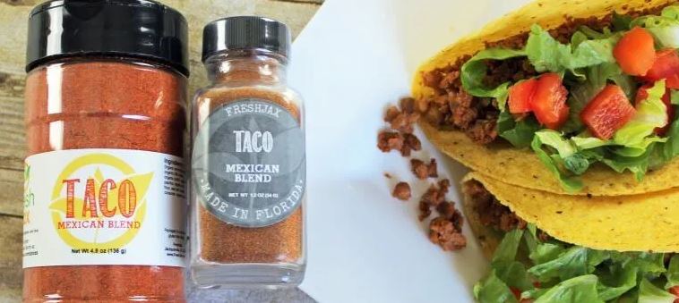 Two Crunchy Tacos Next to a large and a sampler Sized FreshJax Taco Seasoning