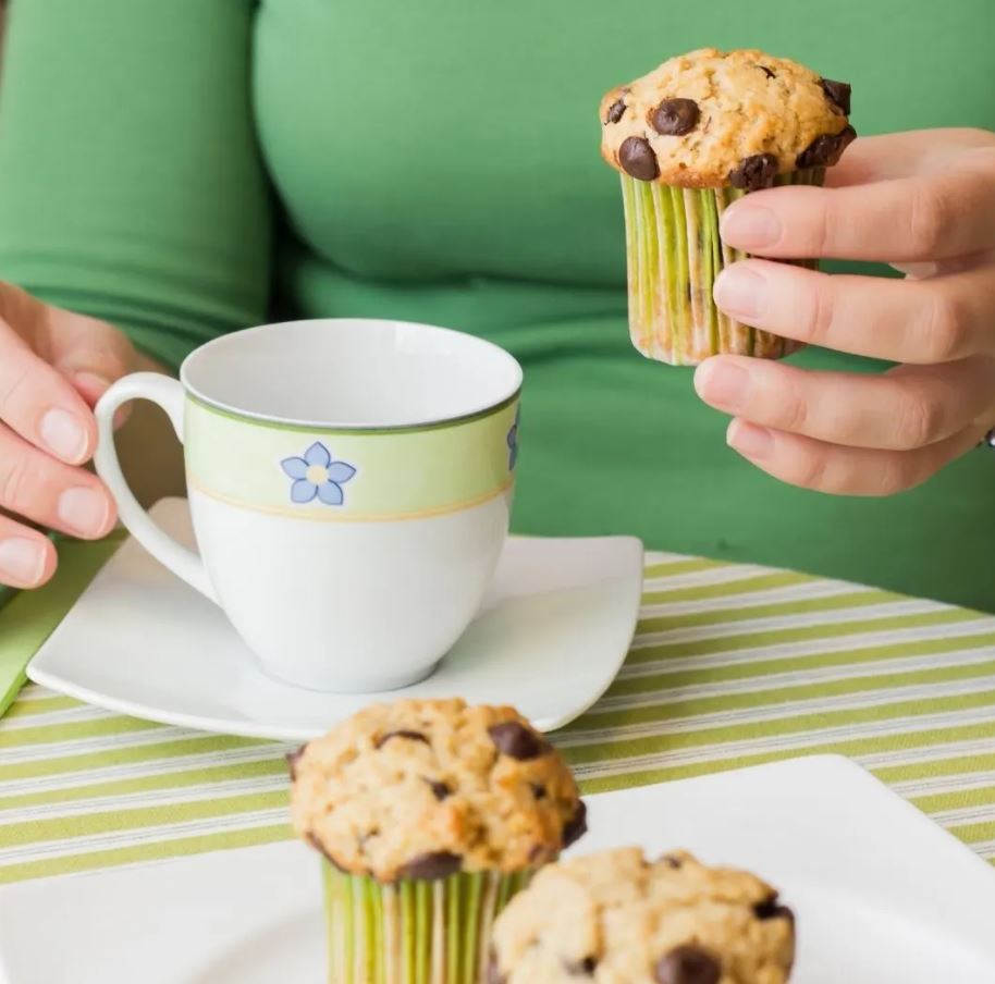 Lady eating muffins and sipping tea