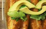 Plant-Based Enchiladas topped with avocados and enchilada sauce