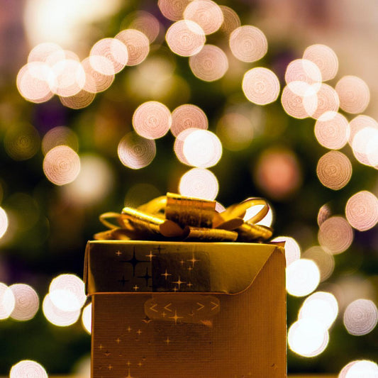 gold gift box with christmas lights in background