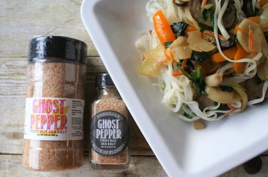Spicy Noodle Stir Fry with mushrooms and carrots next to two bottles of FreshJax Ghost Pepper Sea Salt
