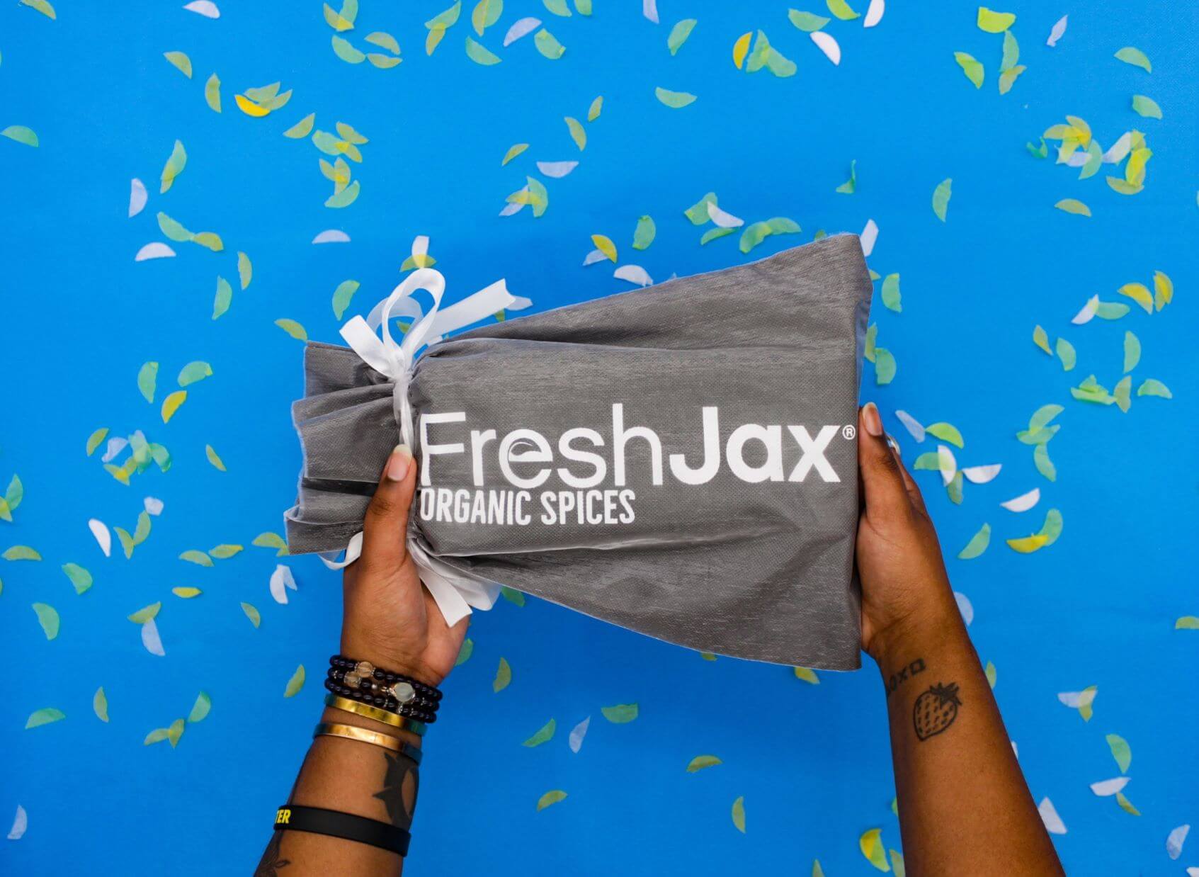 FreshJax silver gift bag with white ribbon surrounded by confetti.