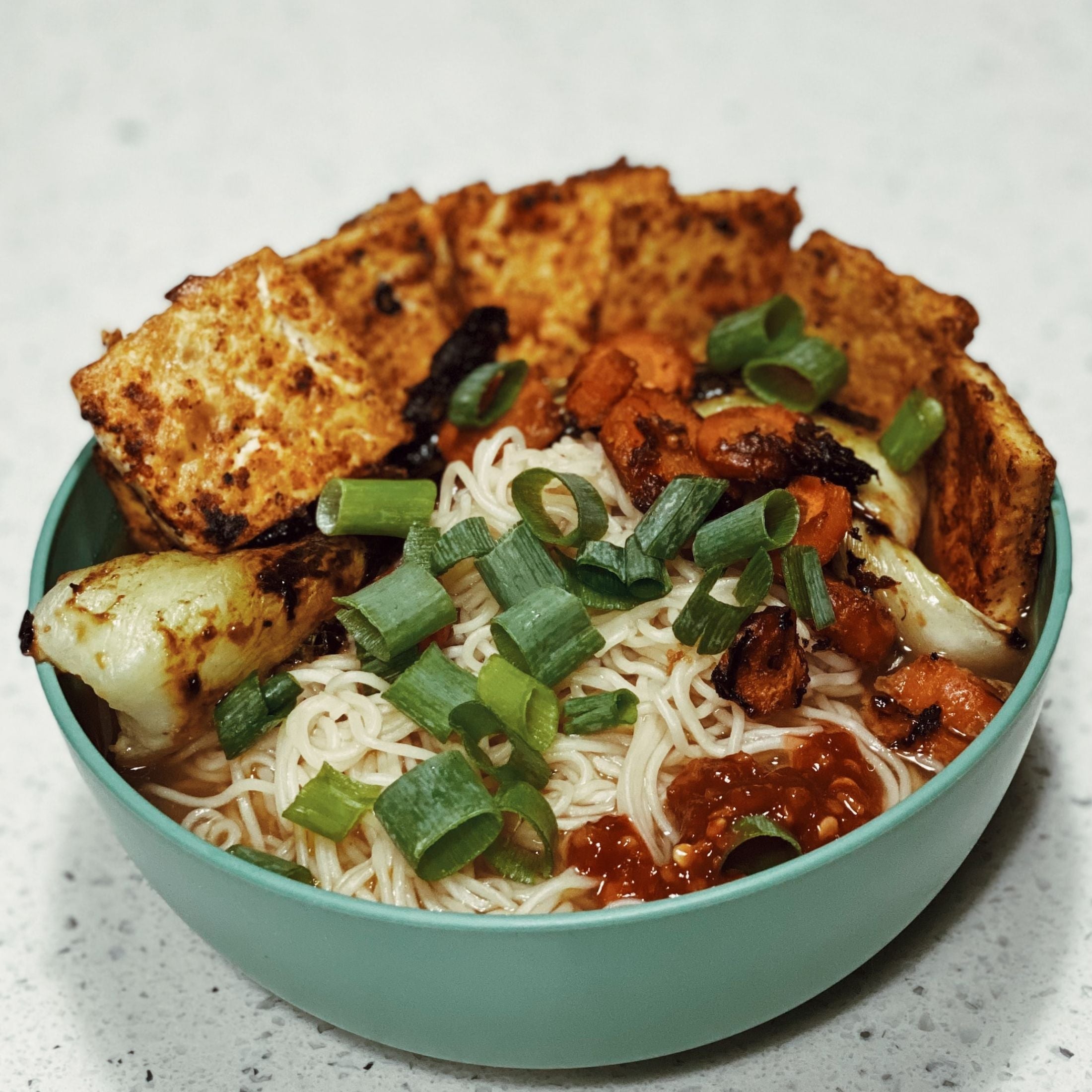 Seasoned Tofu in a bowl with noodles and spicy chili paste