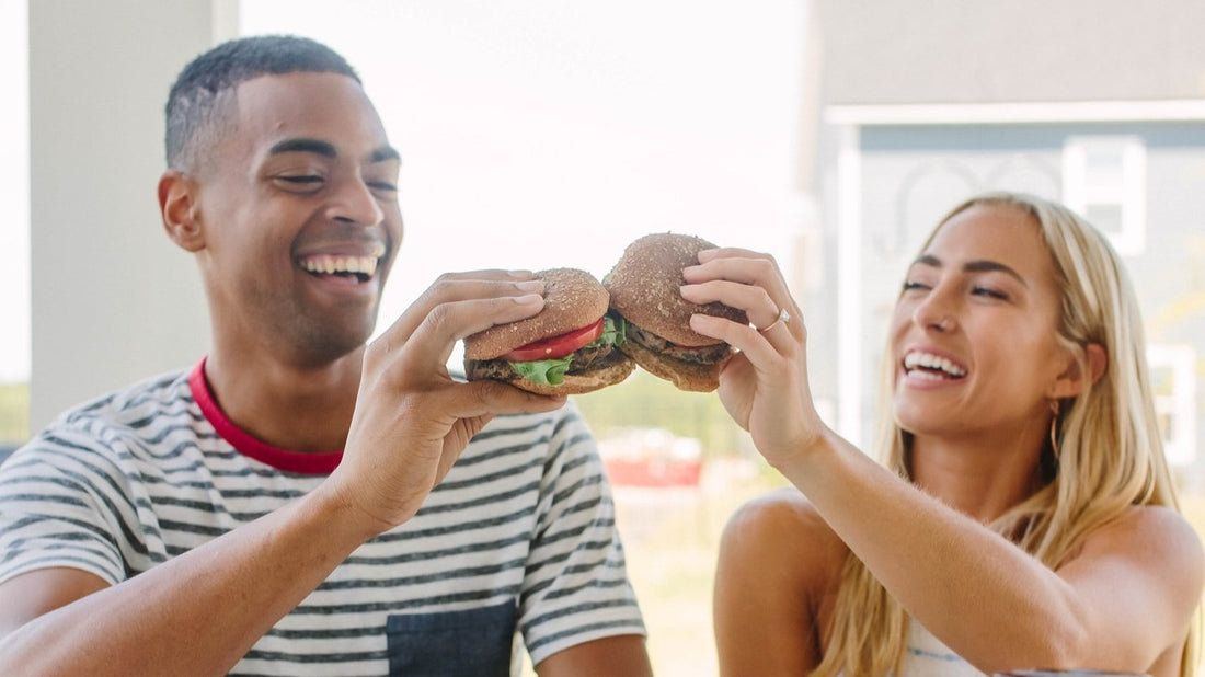 A Man and a Woman using two plant-based burgers to high Five