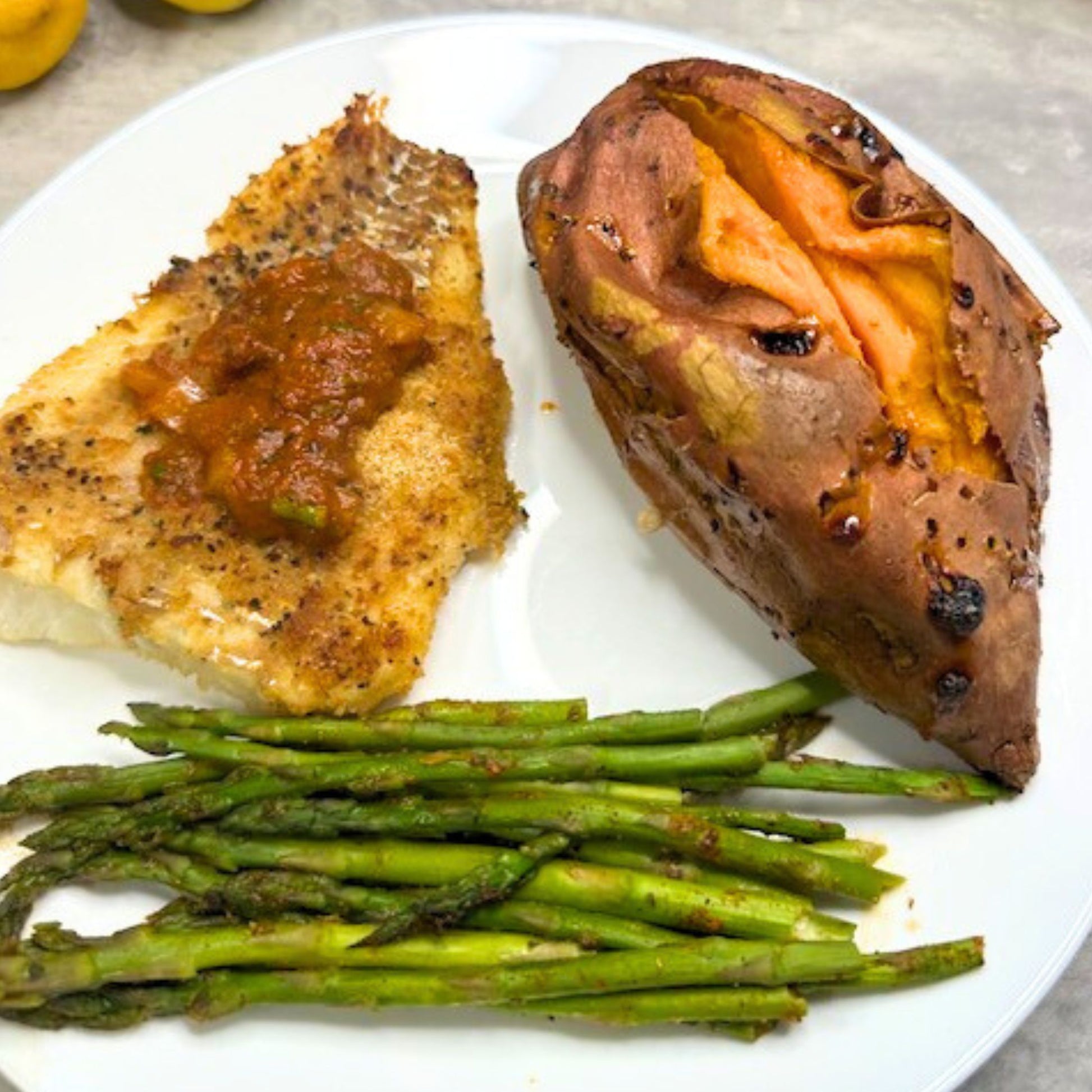 Fish Seasoned with Creole Sauce with a side of Sweet Potatoes and Asparagus
