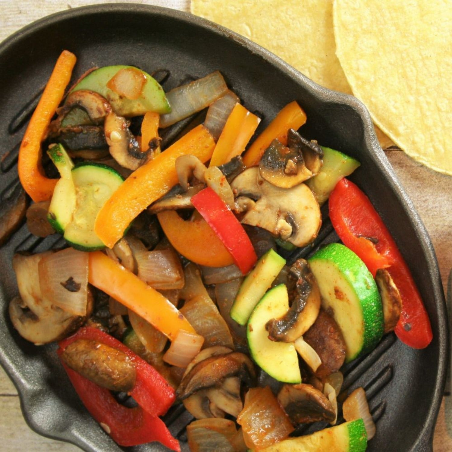 Seasoned fjita veggies in a skillet with tortillas